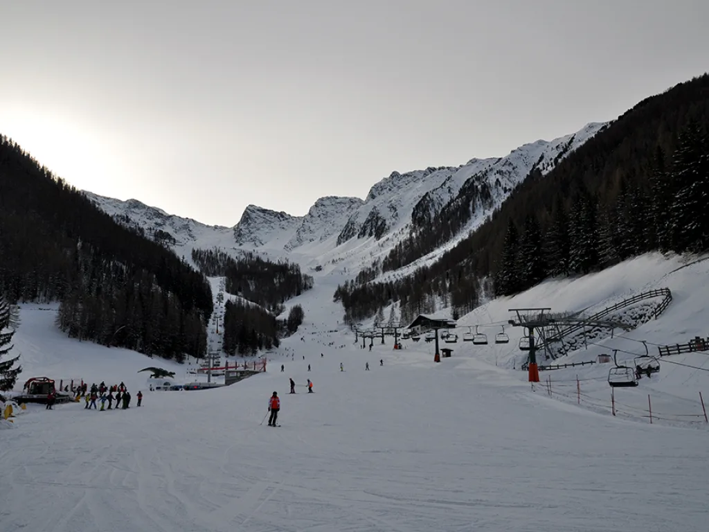 Blick gegen die Sonne auf die Piste und den Sessellift.